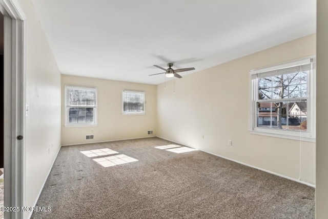 carpeted spare room featuring a wealth of natural light and ceiling fan