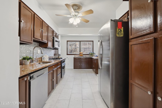 kitchen featuring sink, light stone counters, tasteful backsplash, ceiling fan, and stainless steel appliances