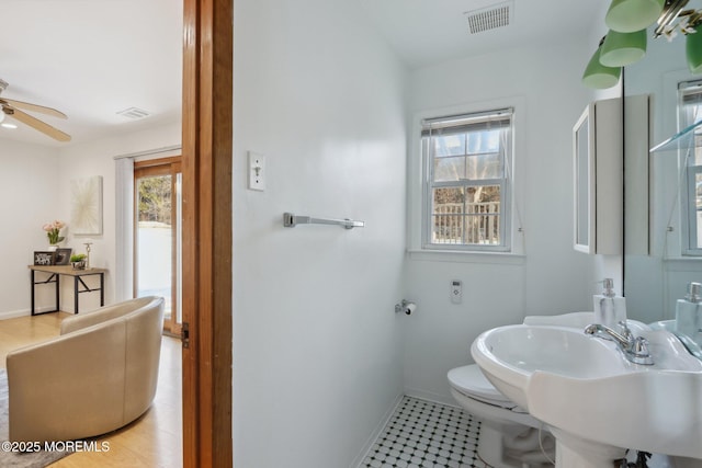 bathroom featuring ceiling fan, a healthy amount of sunlight, toilet, and sink