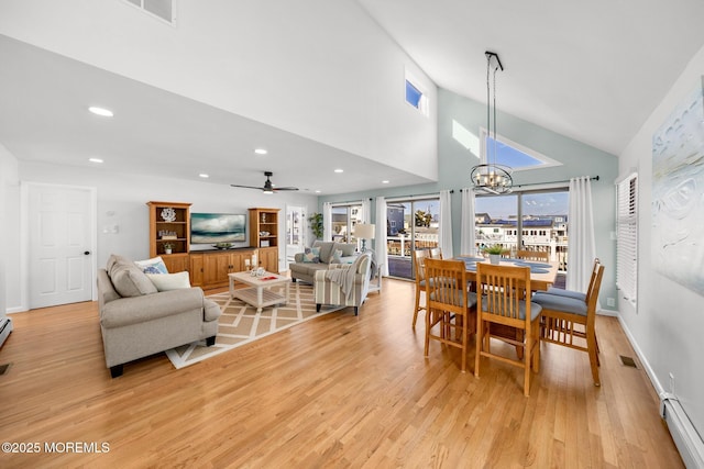 dining area with ceiling fan with notable chandelier, a baseboard radiator, high vaulted ceiling, and light wood-type flooring