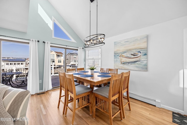 dining area featuring a baseboard radiator, high vaulted ceiling, light hardwood / wood-style floors, and a notable chandelier