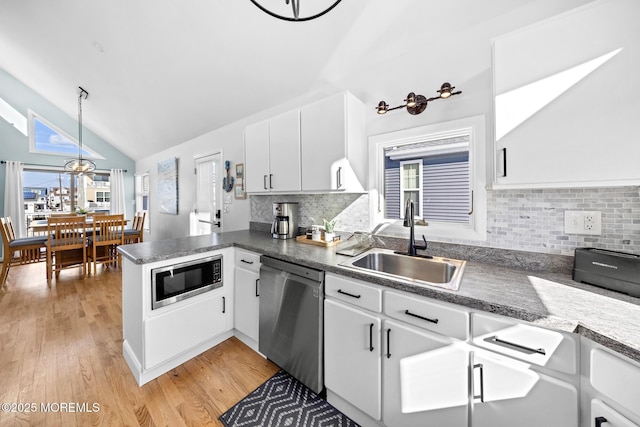 kitchen featuring sink, hanging light fixtures, stainless steel appliances, white cabinets, and kitchen peninsula