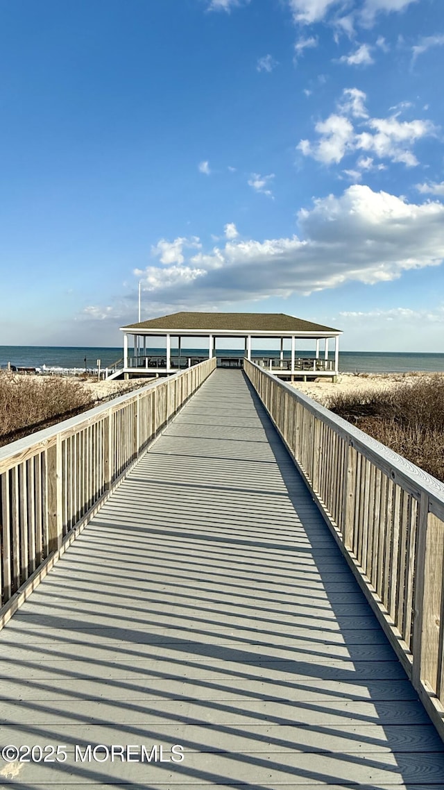 view of dock featuring a beach view and a water view