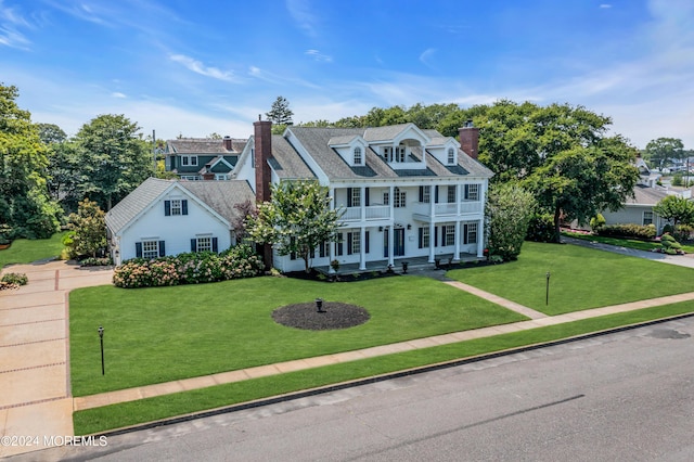 colonial-style house featuring a front yard and a balcony