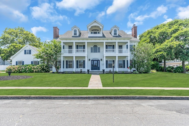 view of front of house featuring a balcony and a front yard