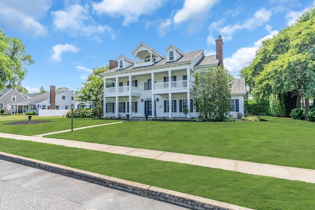 view of front facade with a front lawn and a balcony