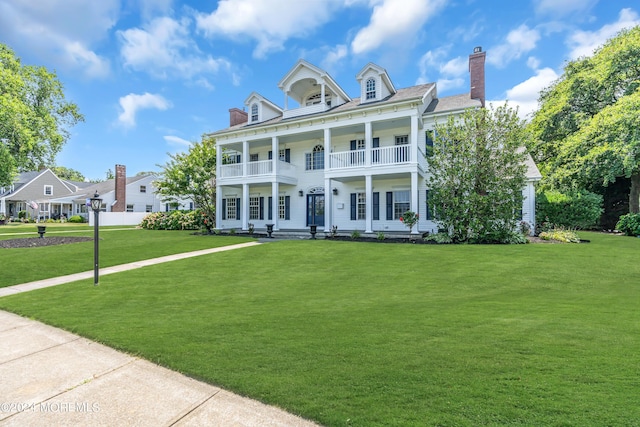 greek revival inspired property with a balcony and a front yard