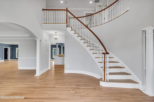 stairway featuring hardwood / wood-style flooring, ornamental molding, and ornate columns