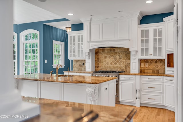 kitchen with sink, white cabinetry, stone countertops, light hardwood / wood-style flooring, and high end stove