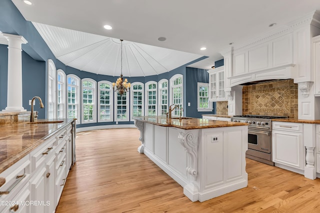 kitchen with sink, designer range, an island with sink, and stone countertops