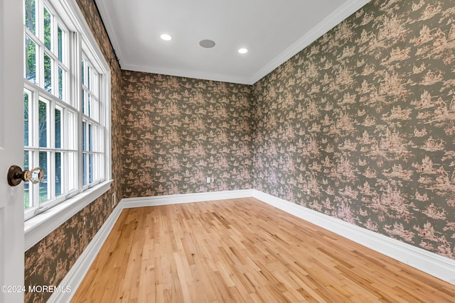 empty room featuring crown molding, wood-type flooring, and a wealth of natural light