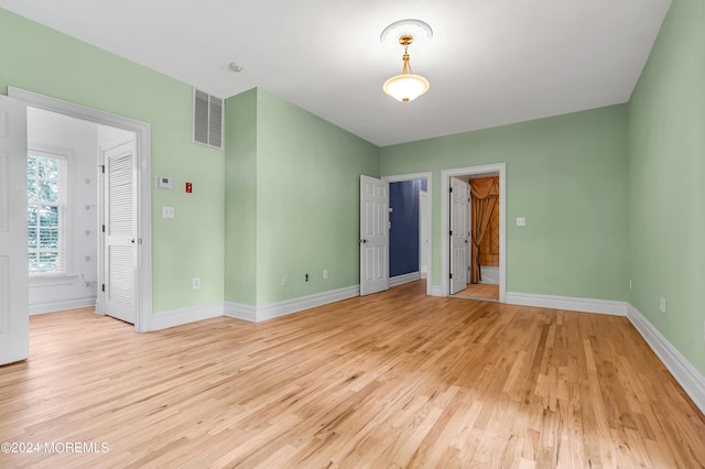 unfurnished bedroom featuring a spacious closet and light hardwood / wood-style flooring