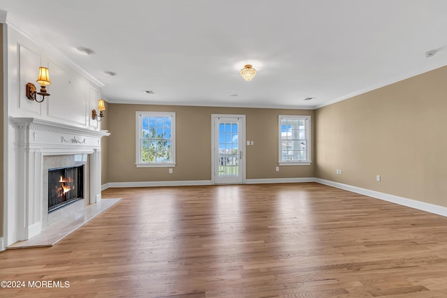 unfurnished living room featuring ornamental molding, a high end fireplace, and light hardwood / wood-style flooring