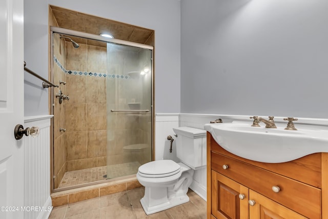 bathroom with a shower with door, vanity, tile patterned flooring, and toilet