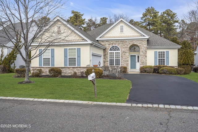 traditional home with driveway, a front lawn, roof with shingles, and stucco siding