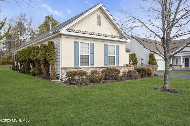 view of side of property featuring stone siding, a lawn, a standing seam roof, and stucco siding