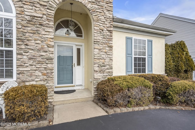 doorway to property with stone siding and stucco siding