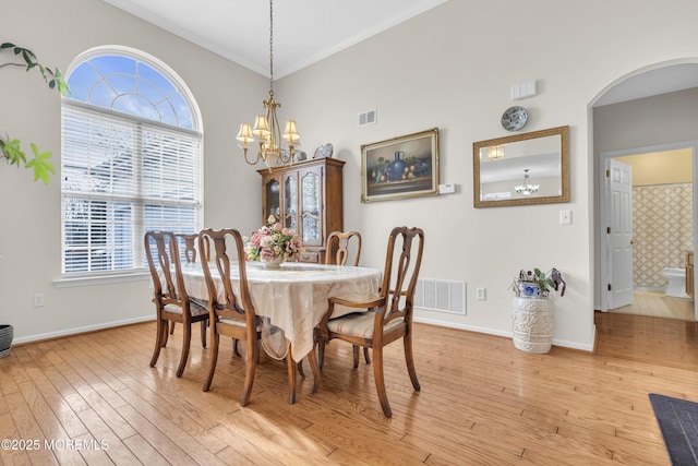 dining room featuring light wood-type flooring, a healthy amount of sunlight, baseboards, and an inviting chandelier