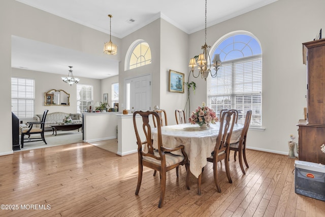 dining area featuring light wood-type flooring, an inviting chandelier, visible vents, and baseboards