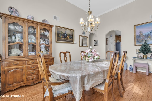 dining area featuring light wood-style flooring, visible vents, arched walkways, and a chandelier