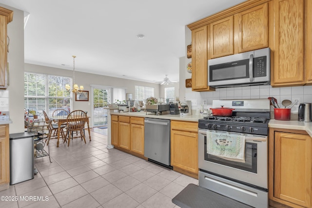 kitchen with light tile patterned floors, tasteful backsplash, appliances with stainless steel finishes, light countertops, and pendant lighting