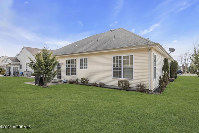 rear view of property with a shingled roof and a yard