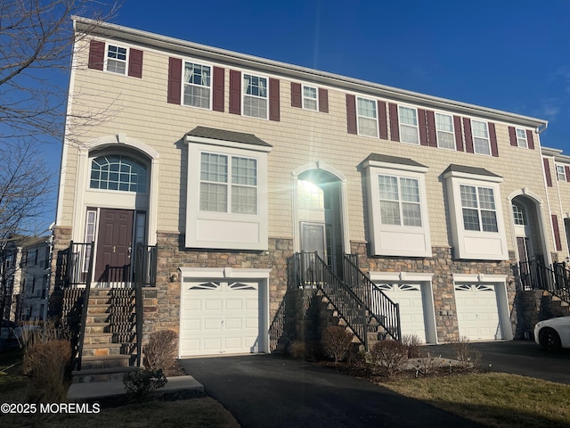 multi unit property with a garage, stone siding, and driveway