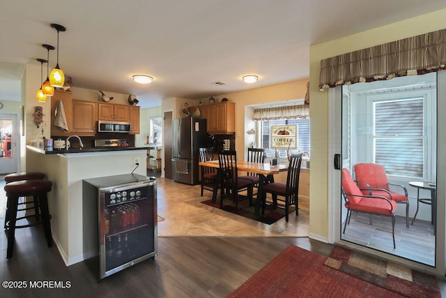 kitchen with pendant lighting, a breakfast bar, appliances with stainless steel finishes, wine cooler, and kitchen peninsula