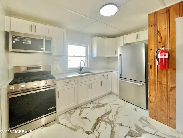 kitchen featuring backsplash, stainless steel appliances, sink, and white cabinets