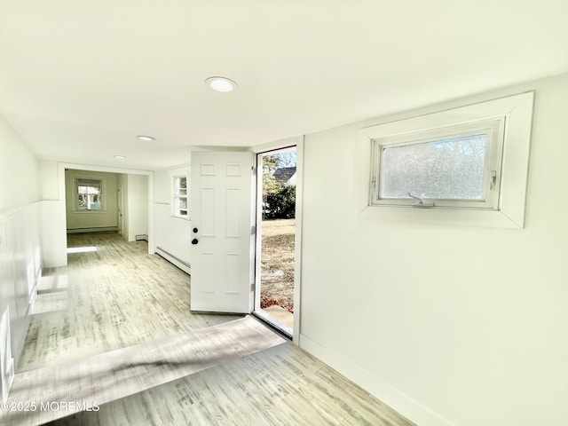 foyer featuring plenty of natural light, baseboard heating, and light hardwood / wood-style flooring