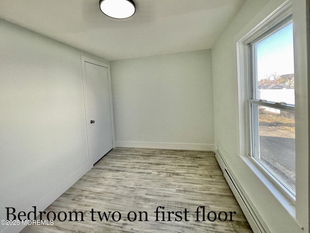 unfurnished room featuring a baseboard radiator and light wood-type flooring