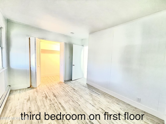 empty room with baseboard heating and light hardwood / wood-style floors