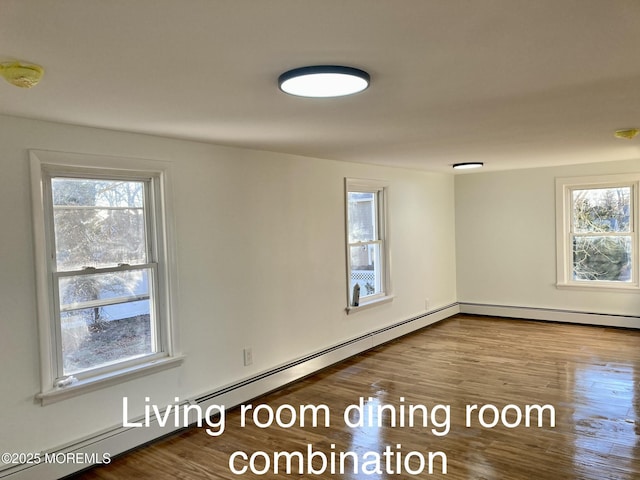 unfurnished room with a baseboard heating unit and hardwood / wood-style floors