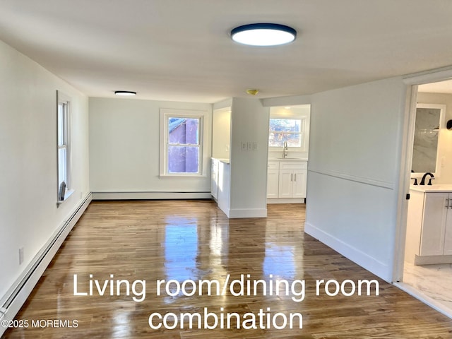 unfurnished room with baseboard heating, sink, and hardwood / wood-style flooring