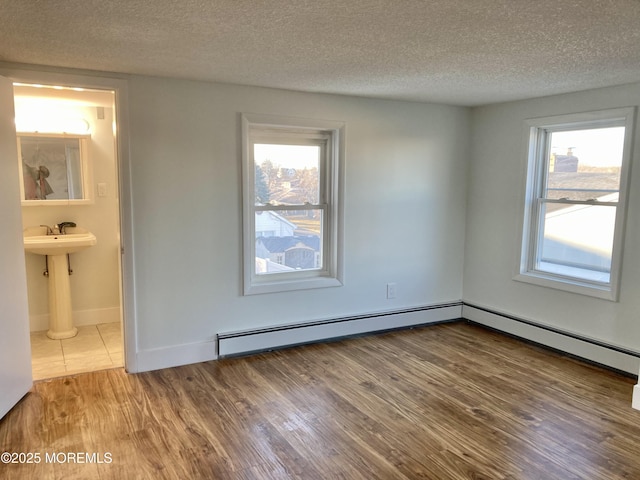 unfurnished room with hardwood / wood-style floors, a wealth of natural light, and a textured ceiling