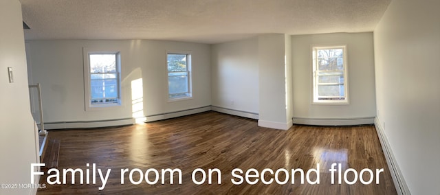 spare room featuring plenty of natural light, dark hardwood / wood-style floors, and a textured ceiling