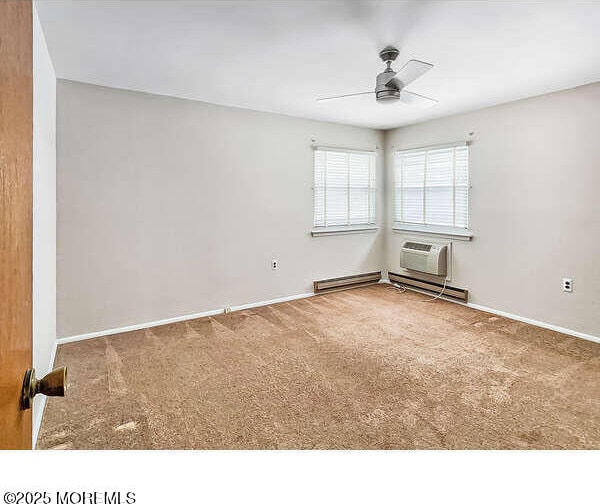 carpeted empty room with a baseboard radiator, a wall unit AC, and ceiling fan