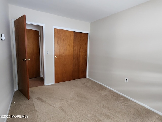 unfurnished bedroom featuring light colored carpet and a closet