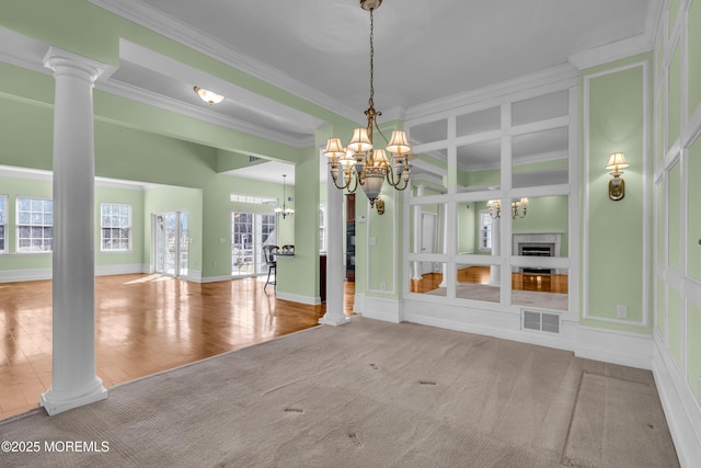 unfurnished dining area featuring a notable chandelier, a wealth of natural light, decorative columns, and ornamental molding