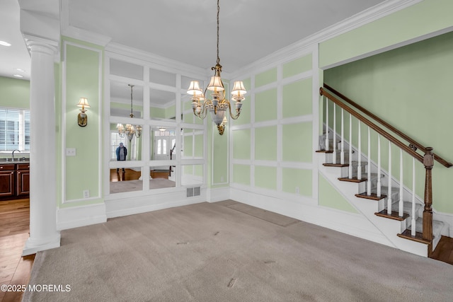 unfurnished dining area with ornate columns, crown molding, sink, and an inviting chandelier