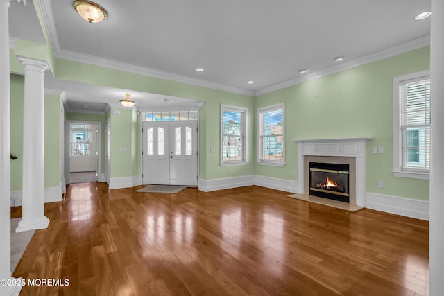 unfurnished living room featuring decorative columns, hardwood / wood-style floors, and a wealth of natural light