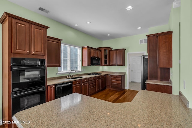 kitchen featuring sink, light stone counters, and black appliances