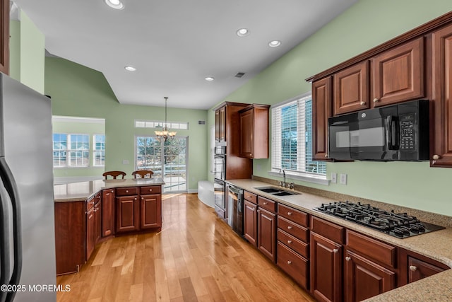 kitchen with sink, an inviting chandelier, hanging light fixtures, black appliances, and light wood-type flooring