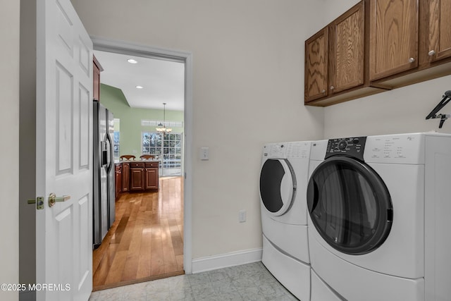 washroom featuring independent washer and dryer, cabinets, and a chandelier