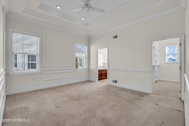 carpeted spare room featuring crown molding, ceiling fan, and a tray ceiling