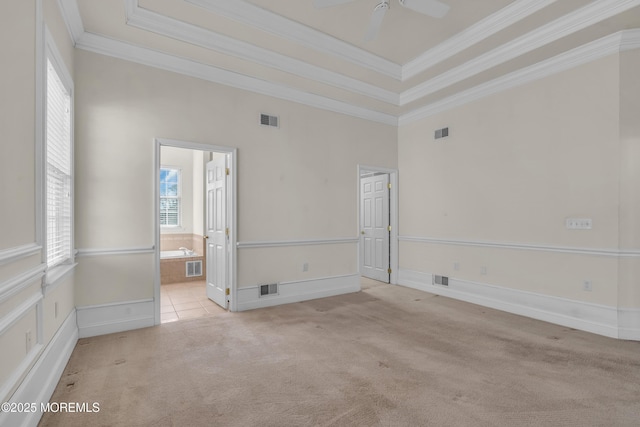 carpeted empty room featuring a raised ceiling, ornamental molding, and ceiling fan