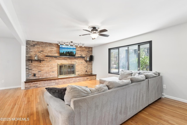 living room with ceiling fan, rail lighting, hardwood / wood-style floors, and a fireplace