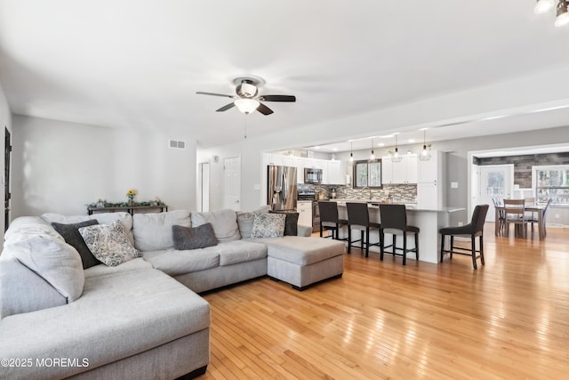 living room with ceiling fan, sink, and light hardwood / wood-style floors