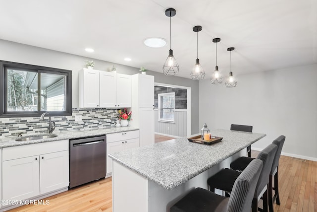 kitchen with white cabinetry, dishwasher, sink, and a breakfast bar area