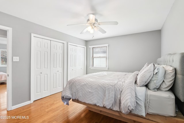 bedroom featuring hardwood / wood-style floors, multiple closets, and ceiling fan